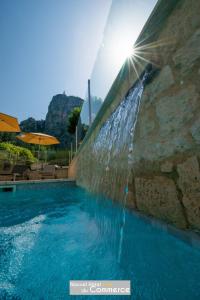 a swimming pool with a water fountain at Nouvel Hôtel du Commerce in Castellane