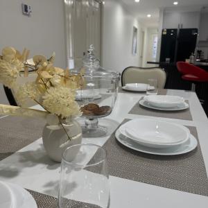 a table with plates and a vase with flowers on it at Mahzan on Braid Private Room 3 in Truganina +6 photos