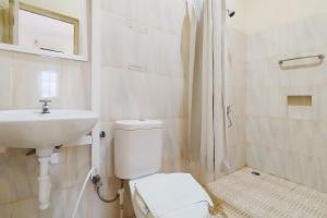 een witte badkamer met een toilet en een wastafel bij RedDoorz near Focal Point Medan in Sunggal