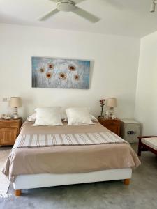 a bedroom with a bed and a painting on the wall at Villa koki Bonheur in Grand-Baie