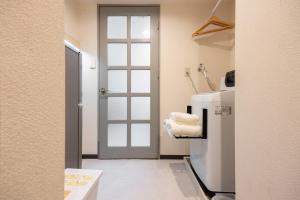 Habitación con puerta y nevera con toallas en Minami-Fukuoka Good Place House, en Fukuoka