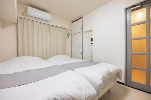 Un dormitorio con una cama blanca y una ventana. en Minami-Fukuoka Good Place House, en Fukuoka
