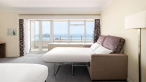 a room with a couch and a chair and a window at Holiday Inn Brighton Seafront by IHG in Brighton & Hove