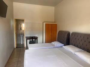 a bedroom with two beds and a table with a sink at Hotel Lupinetti in Jaciara