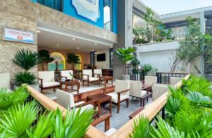 un patio extérieur avec tables, chaises et plantes dans l'établissement Ocean Garden Boutique Da Nang by Haviland, à Đà Nẵng