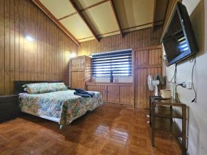 a bedroom with a bed and a flat screen tv at Te Ra'a Travel - Cabaña equipada in Hanga Roa