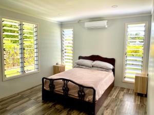 a bedroom with a bed and two windows at Villa Ahava in Pacific Harbour +37 photos