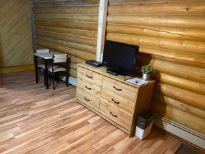 a room with a tv on a dresser with a table at Double G Service in Muncho Lake