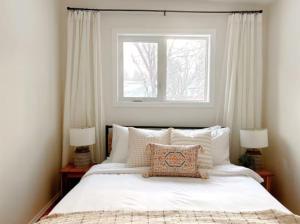 a bedroom with a large white bed with a window at Modern 3BR Near Airport & DT in Calgary