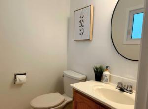a bathroom with a toilet and a sink and a mirror at Modern 3BR Near Airport & DT in Calgary +36 photos