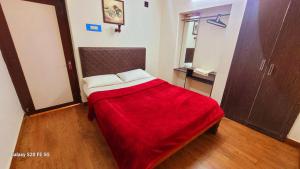 a bedroom with a bed with a red blanket at Green Woods Homestay in Kodaikānāl