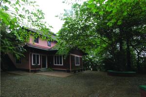 a pink house with trees in front of it at Wayanad One in Wayanad
