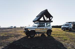 a jeep parked in a field with its roof up at FUUUN Camping Car in Fujinomiya