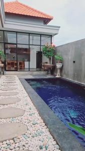 a swimming pool in front of a house at Aksamala Villa Echobeach Canggu in Canggu