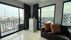 a living room with a couch and large windows at Baan Paknam Budget Hotel in Samut Prakan