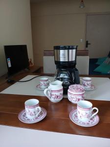 un grupo de tazas y platillos sobre una mesa con una cafetera en Apartment in the historic center of Porto Alegre, en Porto Alegre