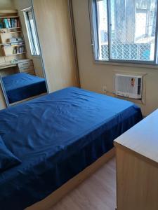 Un dormitorio con una cama azul y una ventana. en Apartment in the historic center of Porto Alegre, en Porto Alegre