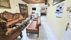 a living room with brown leather couches and tables at Penginapan Bunga Sonsang Padang Syariah in Tabing