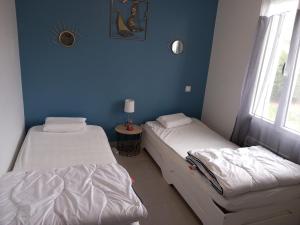 two beds in a room with a blue wall at Maison à Escource avec Jardin et Accès Forêt - FR-1-50-166 in Escource
