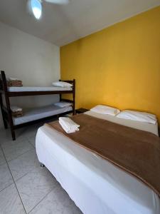 two beds in a room with a yellow wall at Pousada Oceanica Marica in Maricá