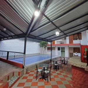 a swimming pool with tables and chairs in a building at Hotel la Isabella SM in Villeta