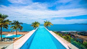 プエルト・バジャルタにあるStunning Beachfront Condo - Sea Views & Poolsのヤシの木が茂る海のそばのスイミングプール