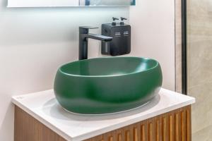 ロサンゼルスにあるLYFE INN & SUITES by AGA- North Hollywood Universal Studiosのバスルームカウンターの上に緑のシンクが備わります。