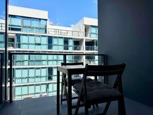 Un balcón con una mesa y sillas y un edificio. en Luxury CBD Escape - 1BR Apartment with Pool & Gym, en Adelaida