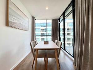 Una mesa y sillas en una habitación con una ventana grande. en Luxury CBD Escape - 1BR Apartment with Pool & Gym, en Adelaida