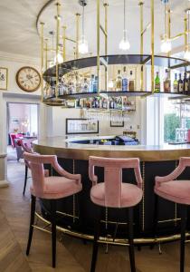 a restaurant kitchen with a bar and chairs at The Slaughters Manor House in Lower Slaughter