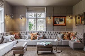 a living room with a large couch and a window at The Slaughters Manor House in Lower Slaughter