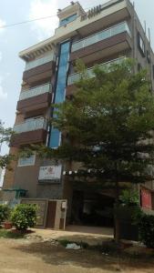 a tall building with a tree in front of it at The Pride Hill-tone in Bangalore