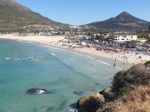 Ein Strand mit einem Haufen Leute im Wasser. in der Unterkunft The Village Apartments in Kapstadt