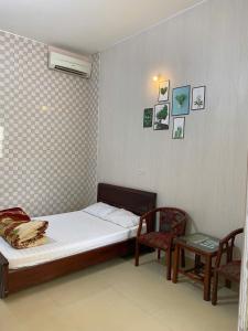 a small bedroom with a bed and two chairs at Nhà Nghỉ Long Lưu in Vinh