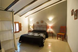 a bedroom with a bed and two tables and a chair at Complejo Rural La Belluga in Segorbe