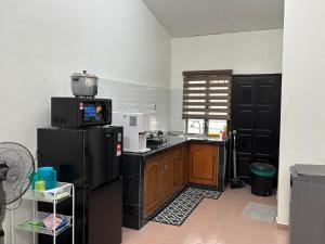 a kitchen with a black refrigerator and a microwave at Rafeeqs Homestay in Teluk Intan