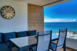 a living room with a clock and a table and chairs at New sunset views in Torrox Costa
