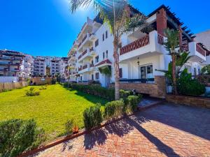 a view of a building with a lawn and palm trees at Apartment Residence Al Kassaba, Beach, Pool, Fast Wifi in Oued Laou