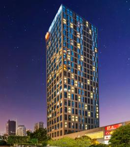 广州Poly Pivot International Aparthotel Guangzhou East Railway Branch - Free Shuttle Bus to Canton Fair Complex During Canton Fair Period的一座高大的建筑,晚上有很多窗户