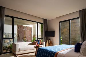 a bedroom with a bed and a couch and a window at Aahana Village Bali in Canggu +42 photos