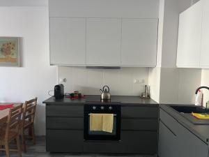 a kitchen with a black stove and white cabinets at APARTAMENT HELSINKI in Krakow