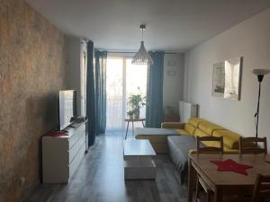 a living room with a yellow couch and a table at APARTAMENT HELSINKI in Krakow