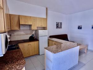 Una cocina con refrigerador blanco y gabinetes de madera. en Vela el Vent 1, en Sant Carles de la Ràpita