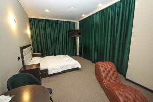 a hotel room with a bed and green curtains at Da Vinci Hotel in Almaty