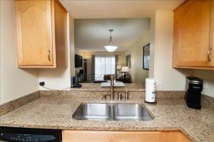 a kitchen with a sink and a living room at Mystic Sands I Steps to Beach I Free activities condo in Saint Augustine Beach