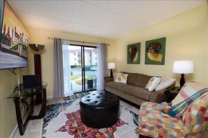 a living room with a couch and a table at Mystic Sands I Steps to Beach I Free activities condo in Saint Augustine Beach