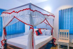 a bedroom with a canopy bed and a chair at Maasai Koroga Hotel & Apartments in Mombasa +69 photos