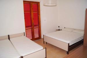 two beds in a room with red shuttered windows at Tra Mare e Collina c'è Belmare in Montecorice
