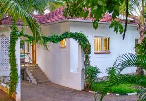 a white house with a red roof at Maasai Koroga Hotel & Apartments in Mombasa