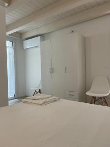 a white bedroom with a bed and a chair at Villa AMARE in Caorle